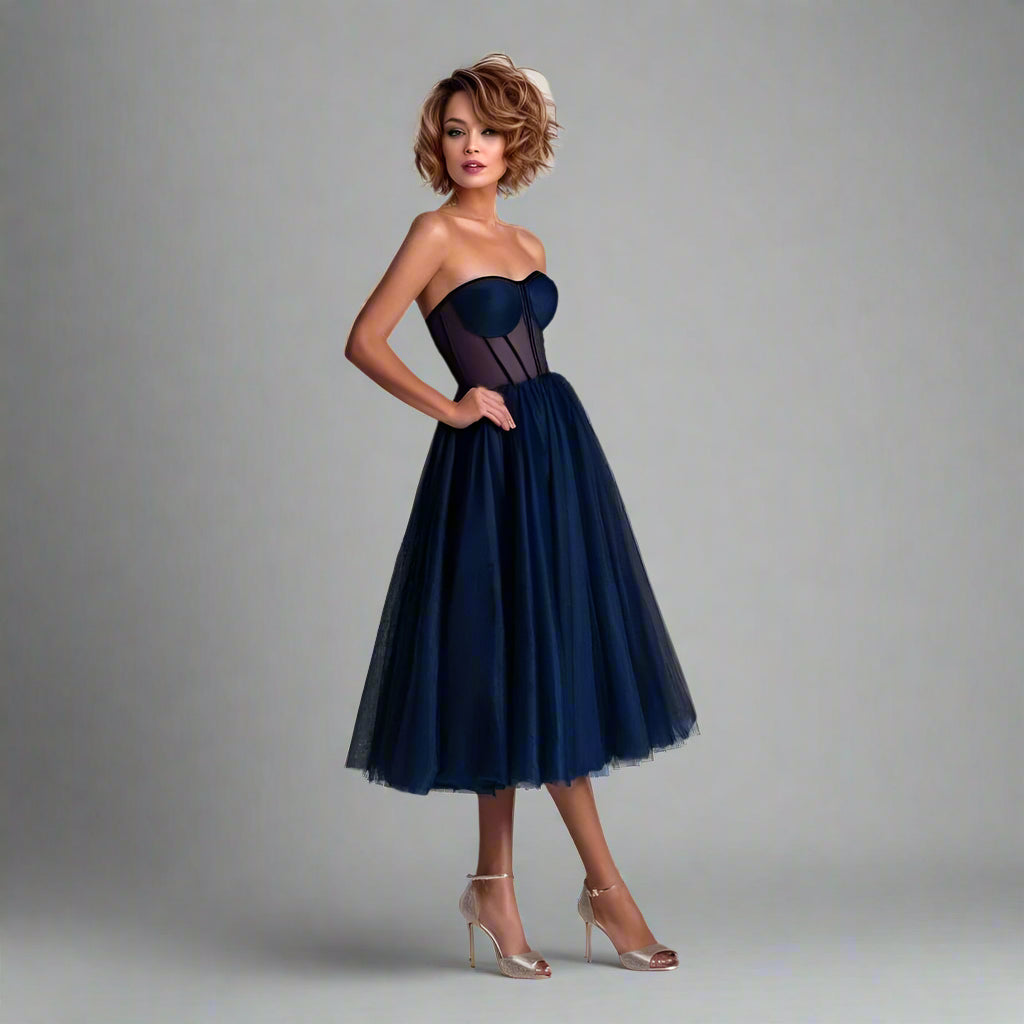 Woman wearing navy blue Vanessa tea-length formal dress with a sheer bodice and pleated bra pads.