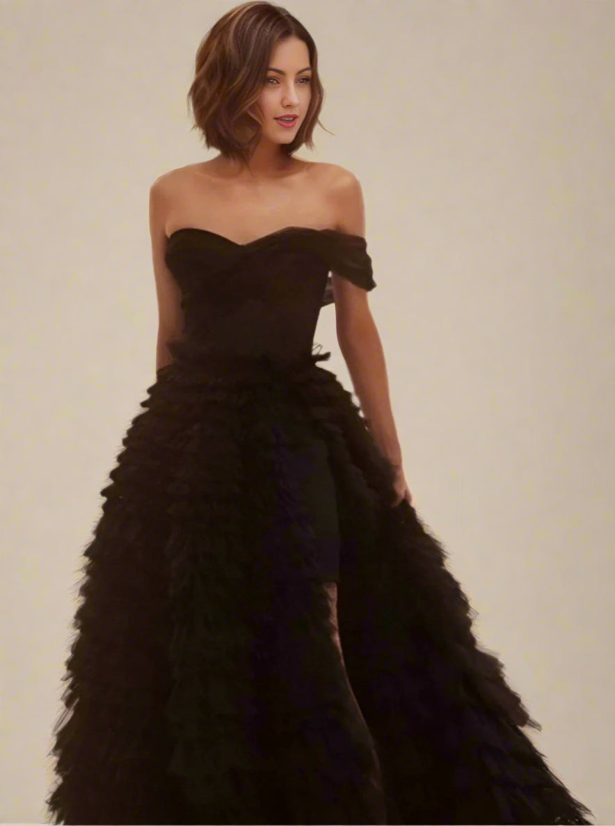 Close-up of the pleated one-shoulder neckline and tiered skirt on black formal dress.