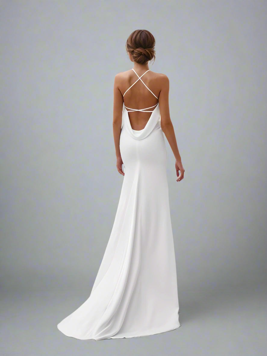 Bride posing in a halter backless mermaid wedding gown with cross-back straps.