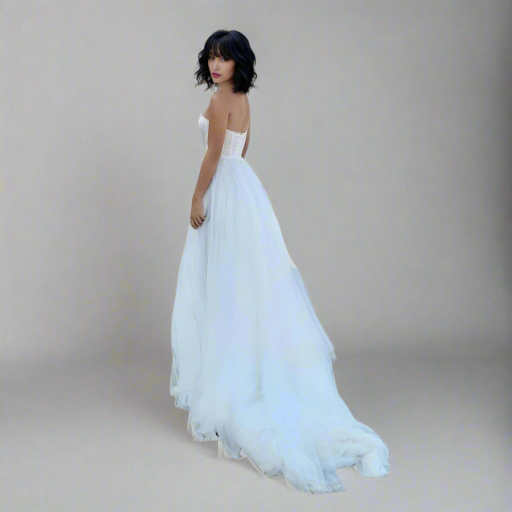 Woman with balck hair showing back of the Vivian Wedding Dress with a long train.