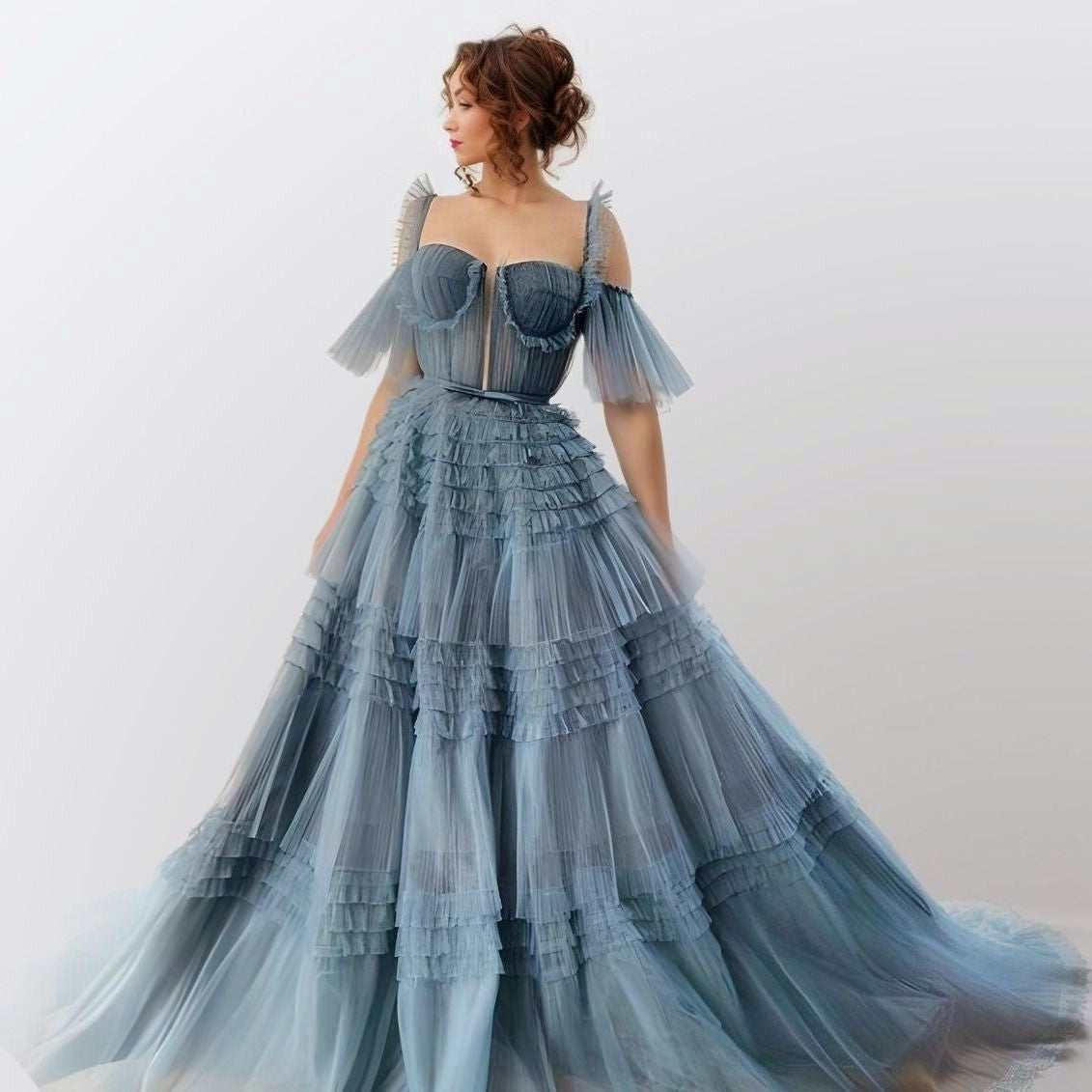 Woman wearing Willow Formal Dress in dusty blue showing tiered ruffled gown with sweetheart neckline.