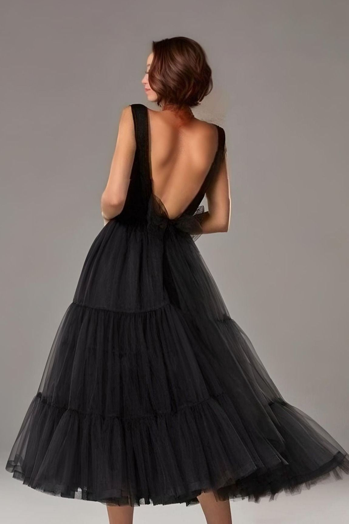 Woman in black tea-length prom dress with a deep V-cut and illusion details