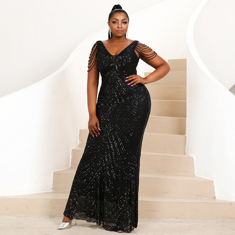Model showcasing a black sequined mermaid gown with a V-neckline and beaded cap sleeves, perfect for an evening event or prom.
