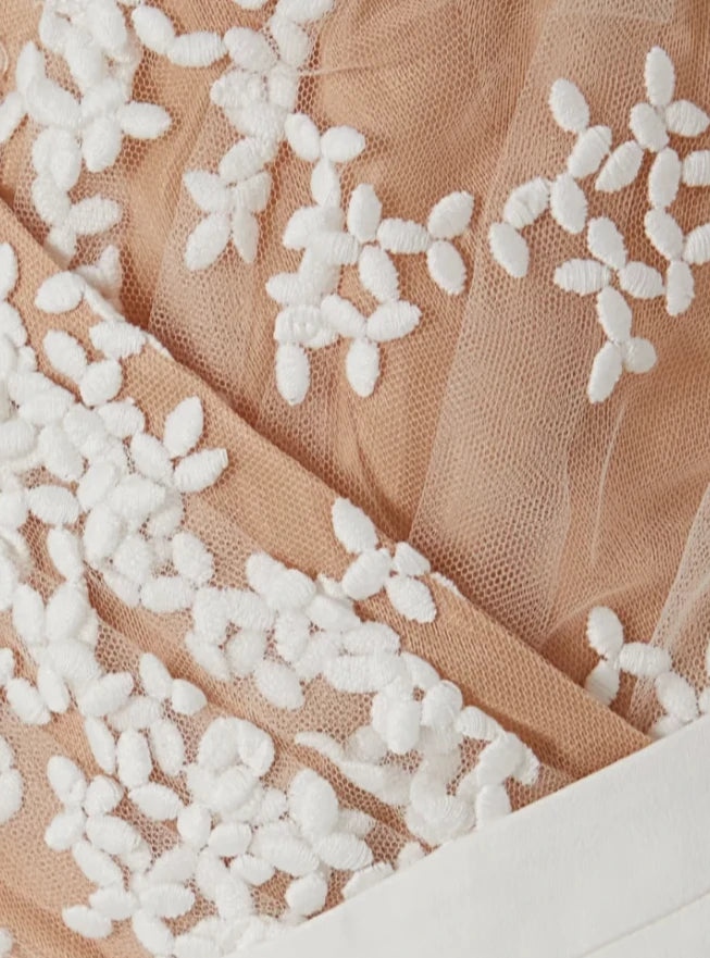Close-up of intricate lace appliqués on nude-toned bridal jumpsuit top.