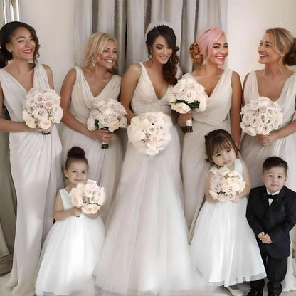 Happy bridal party, bride with bridesmaids holding bouquests, flower girls with flowers and a ring bearer.