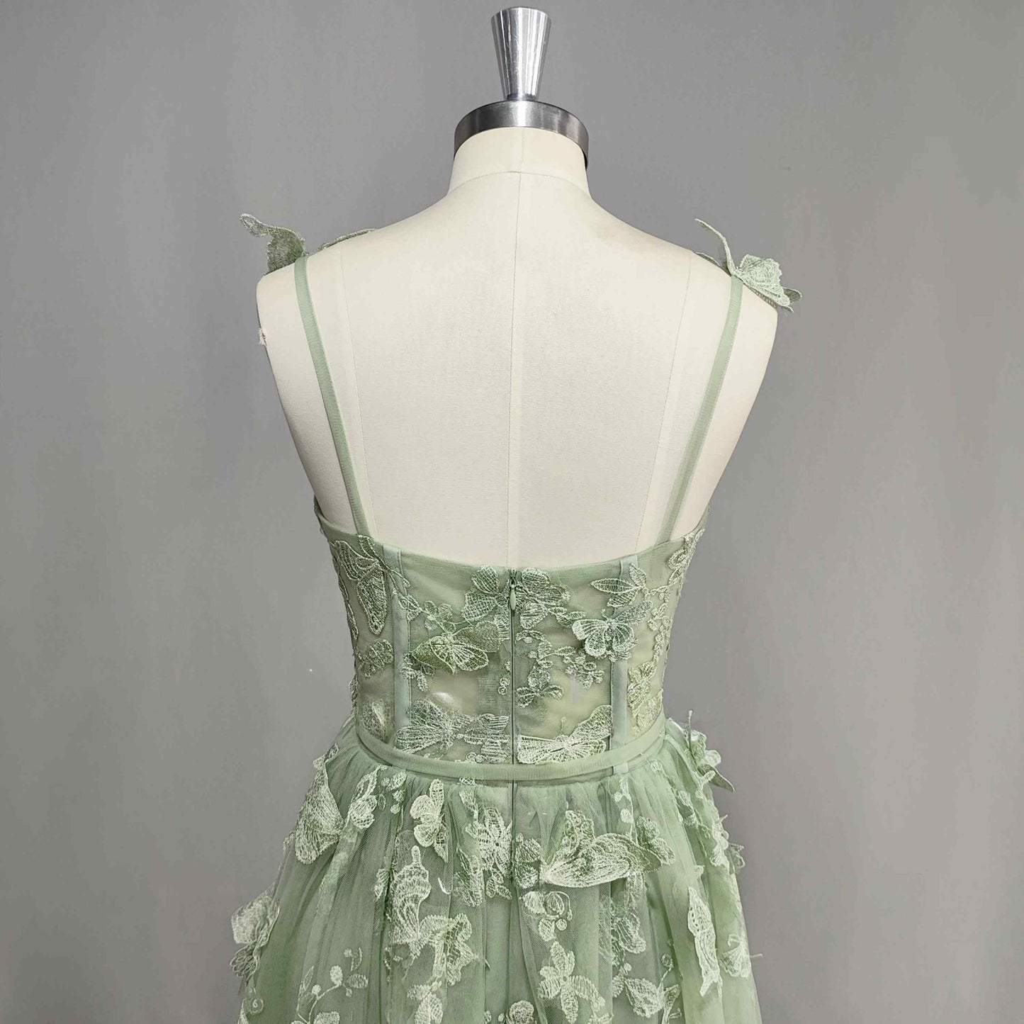 Back detail of sage green tulle prom dress with 3D butterfly appliques and spaghetti straps.