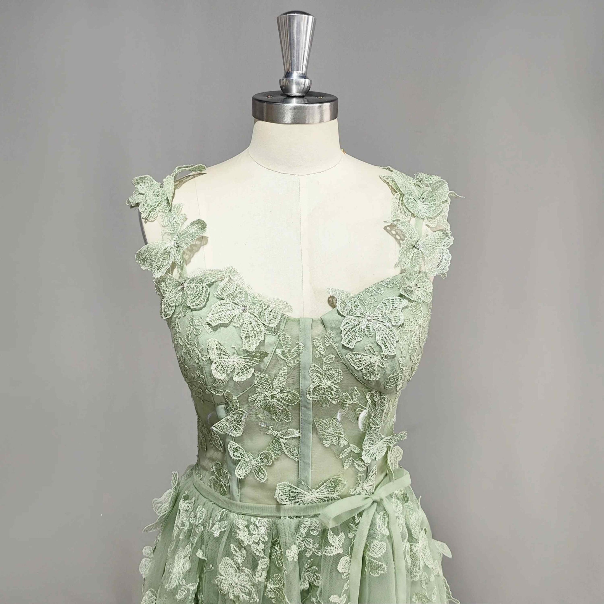 Detail of sage green prom dress with 3D butterflies, boning and sweetheart neckline.