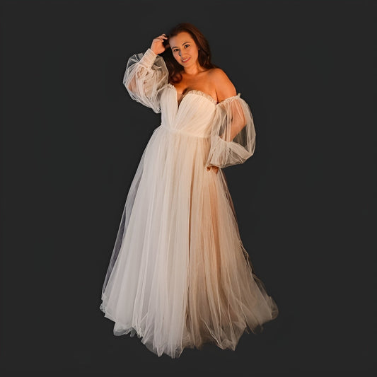 Model showcasing a plus-size A-line bridal gown with long puff sleeves, boat neck, and a sweep train, ideal for a beach or boho wedding.