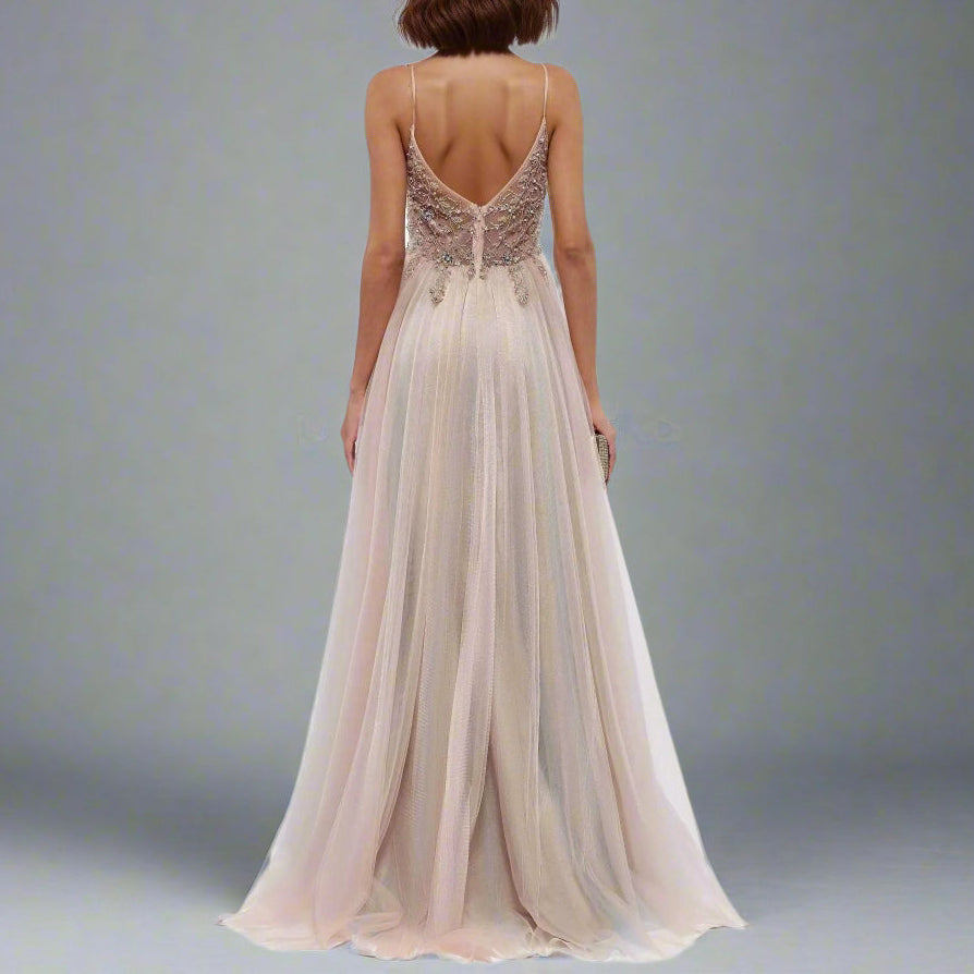 Woman wearing a long, elegant dress with intricate back design on a grey background