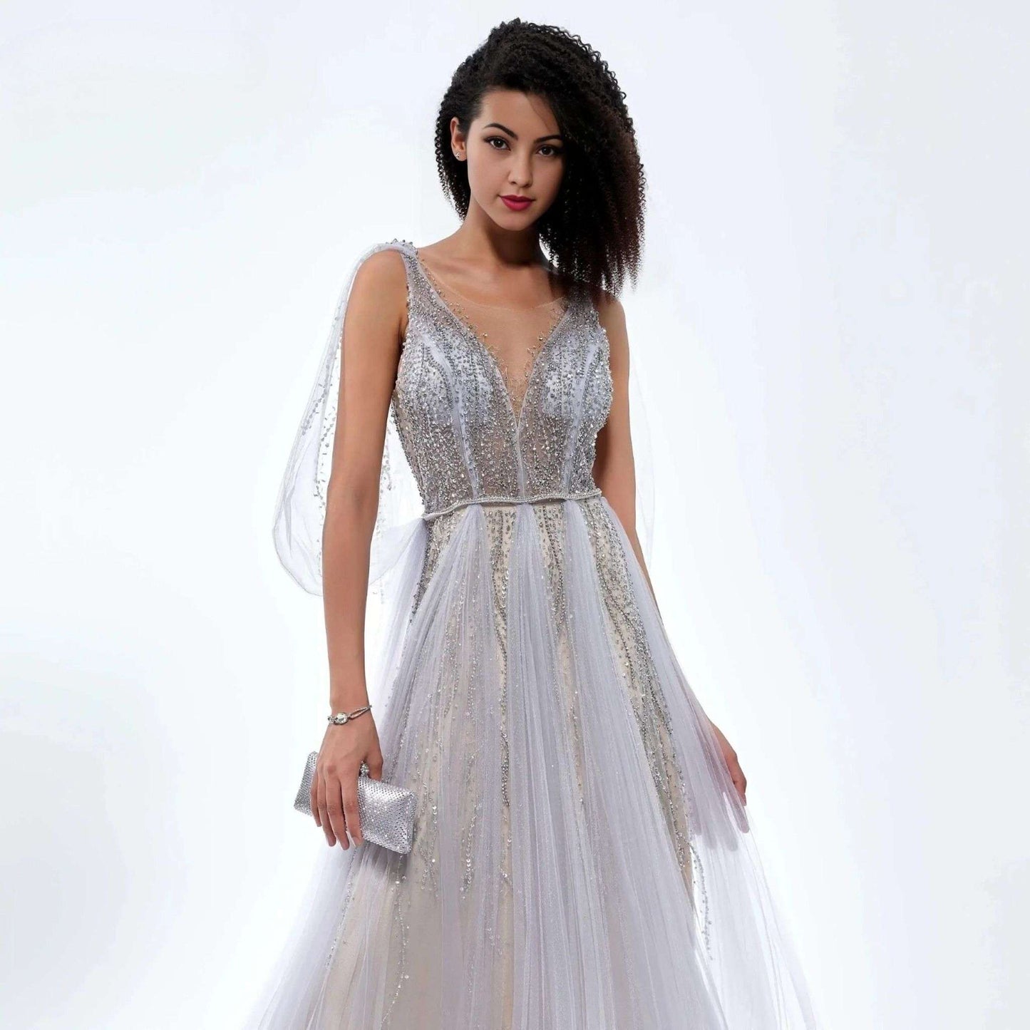 Woman wearing a silver sparkling beaded evening prom gown with a flowing tulle skirt