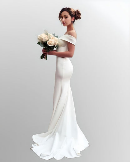 Bride with a bouquet wearing a satin wedding dress with a sweetheart neckline and off-the-shoulder sleeves, designed with a fitted mermaid silhouette and sweep train.