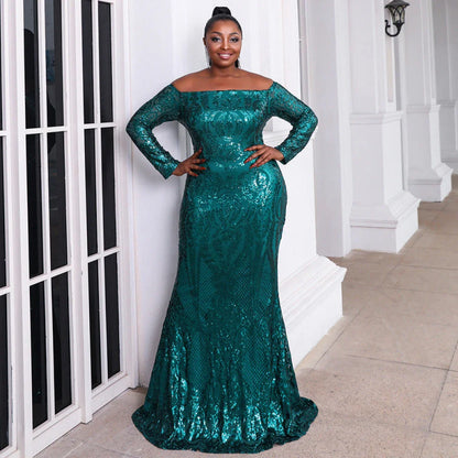 Model showcasing a full-length emerald green gown with long sleeves and boat neckline, crafted with lace-like sequin detailing for a glamorous look.