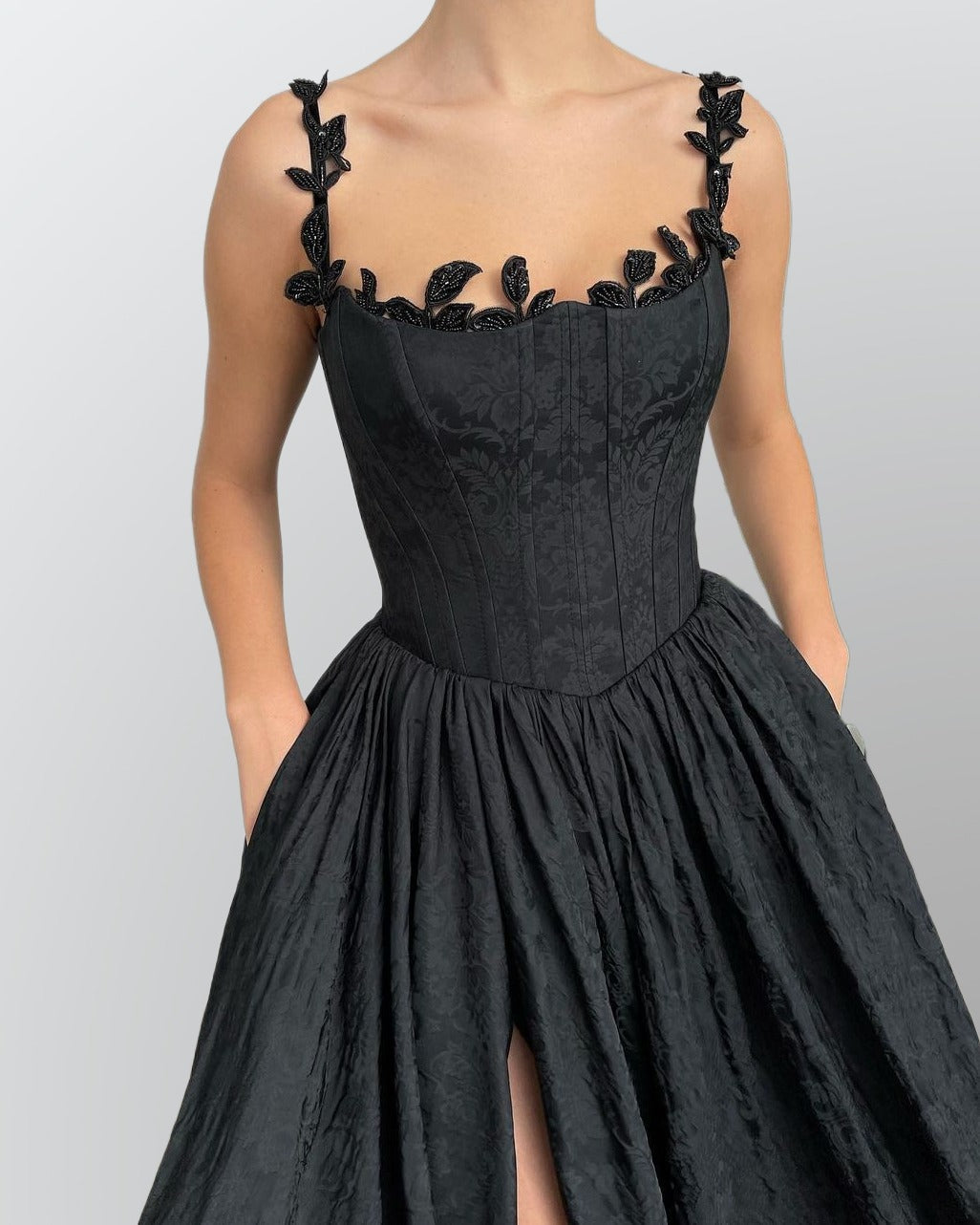 Detail of bodice showcasing a black wedding gown with leaf-like lace appliques.