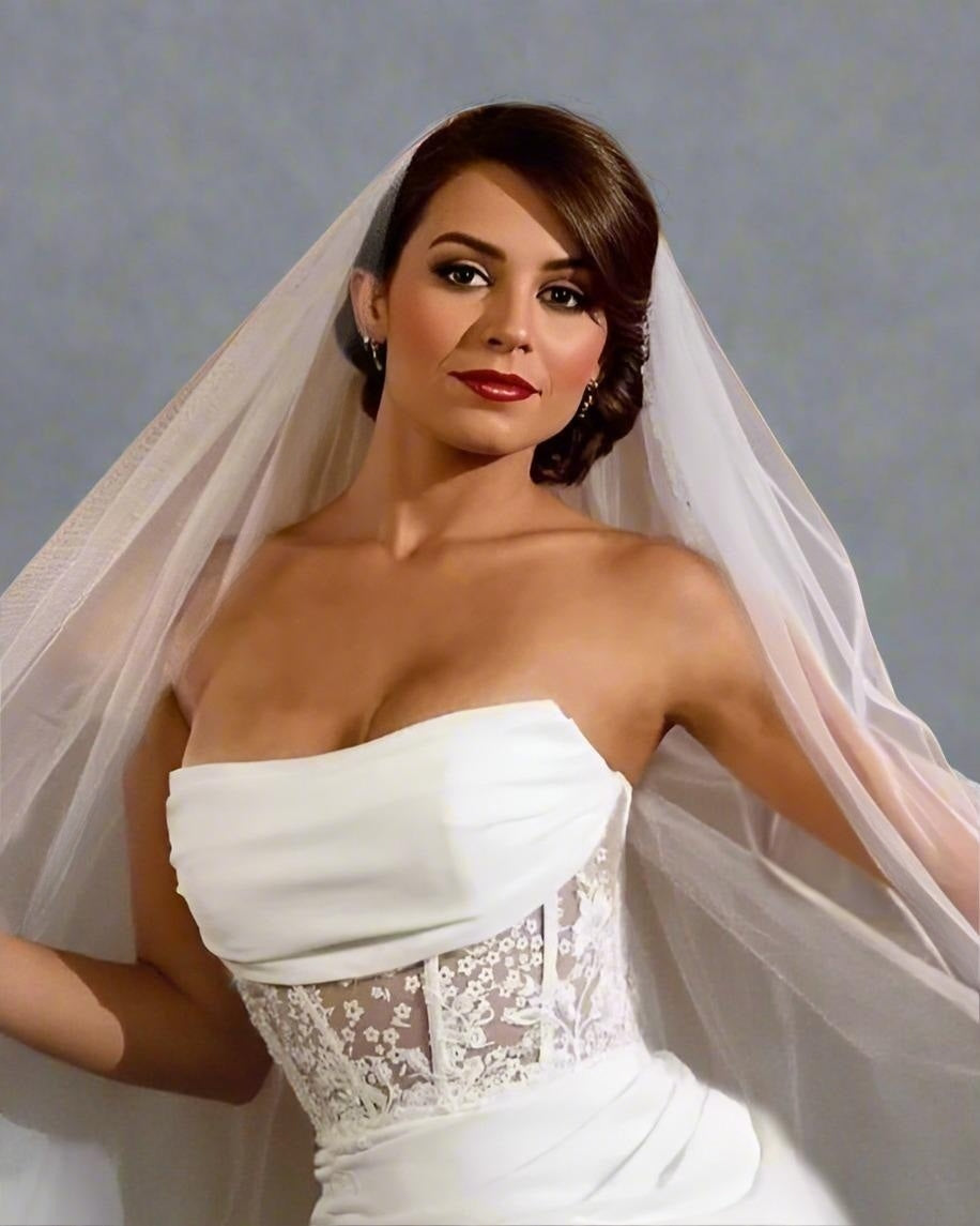 Woman wearing a white wedding dress with a veil against a gray background