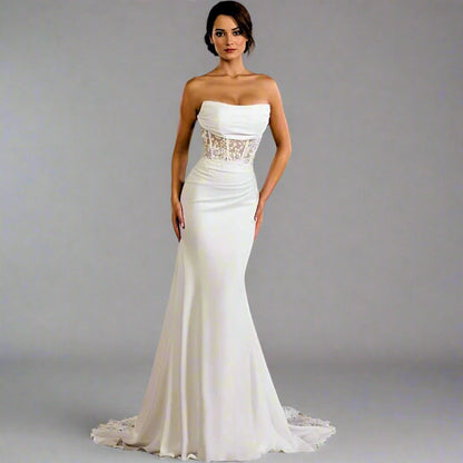 Woman wearing a strapless white wedding dress with lace detailing on a gray background