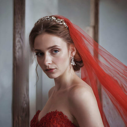 Woman headshot wearing bridal veil in rich red color from tulle and cut edge detail.