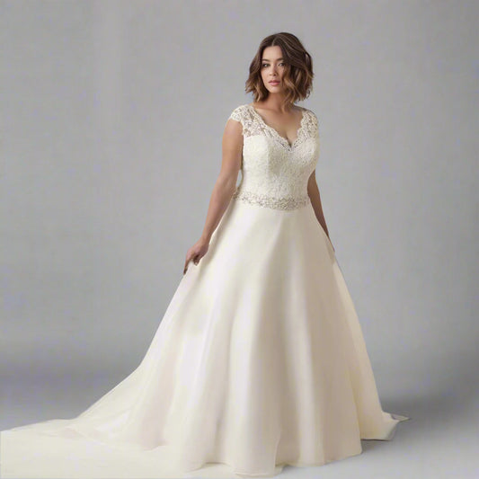 Bride wearing SALMA plus-size wedding dress, showcasing V-neck and cap sleeves.