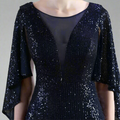 Woman showing detail of navy sequin dress on against a neutral background