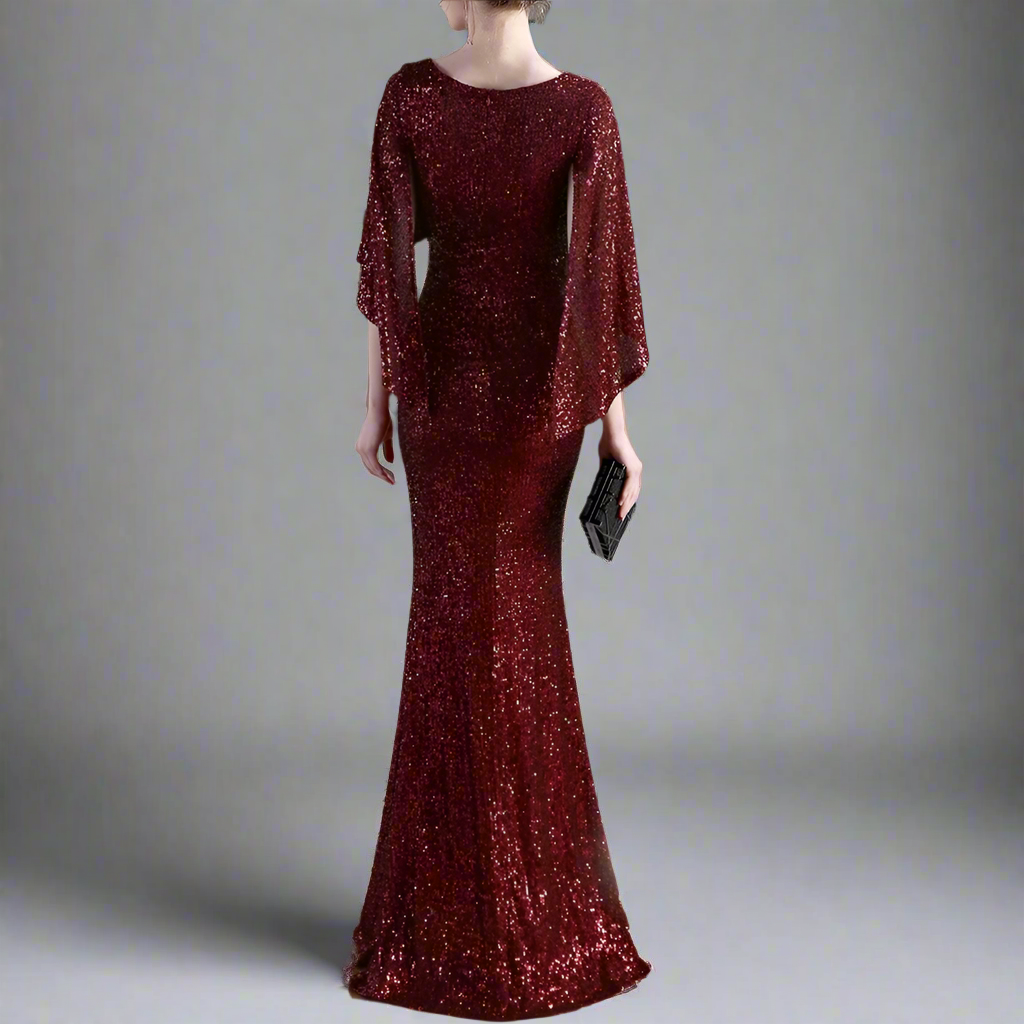 Woman wearing a burgundy sequin dress with bat sleeves from back.