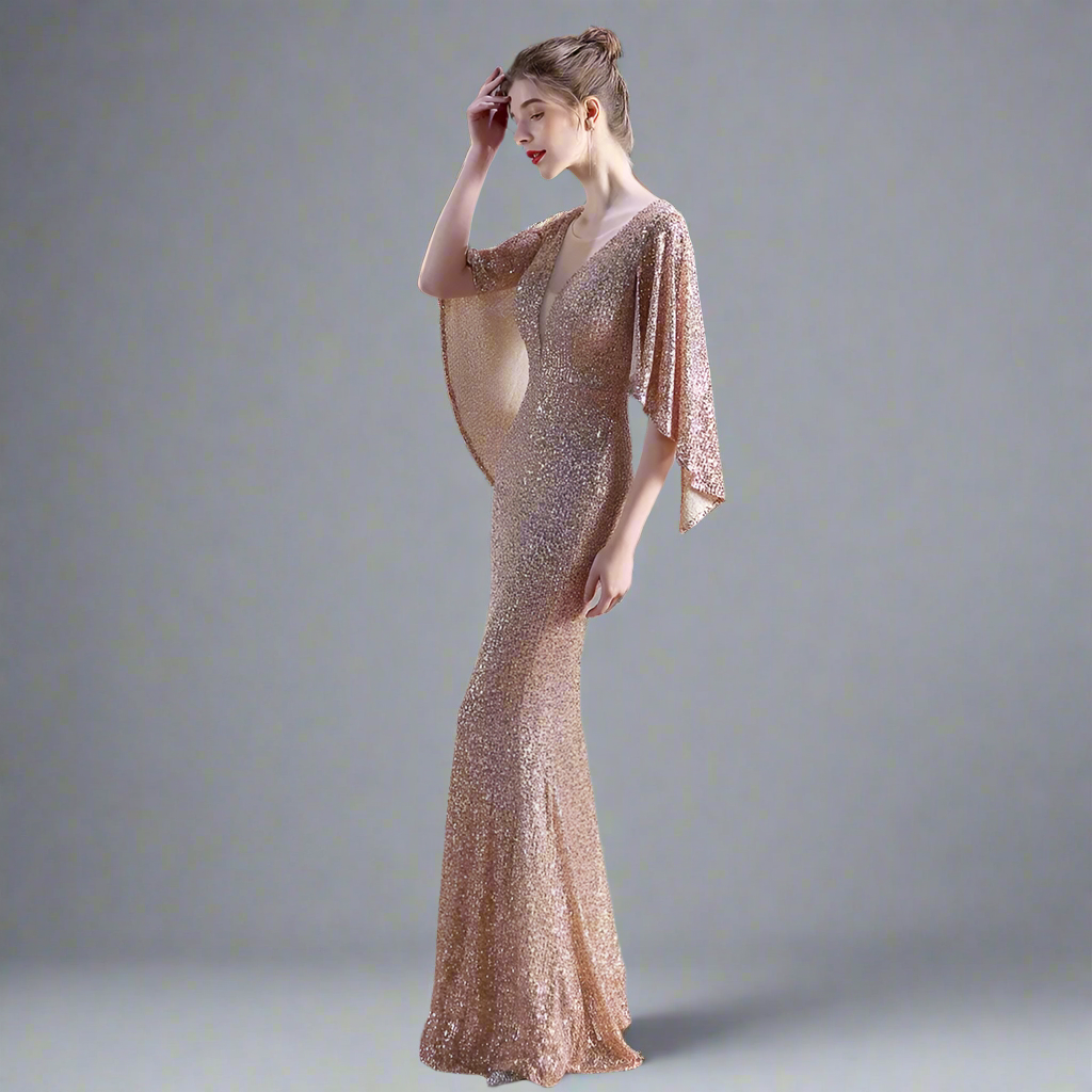 Woman in a gold sparkly evening gown standing in a modern studio setting.