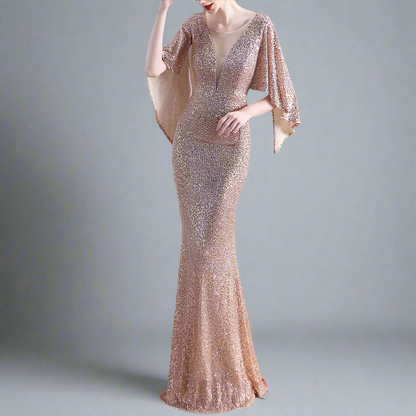 Woman wearing gold sparkly evening gown with cape-like sleeves.