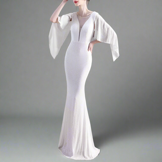 Woman wearing a white evening gown with bell sleeves in an indoor setting.