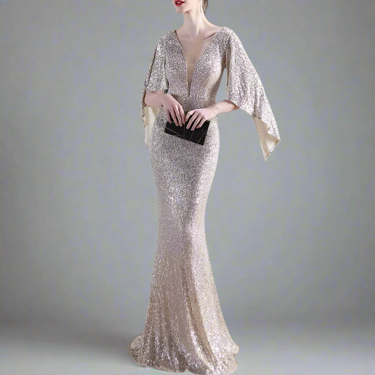 Woman in a sparkly evening gown holding a black clutch in an indoor setting.