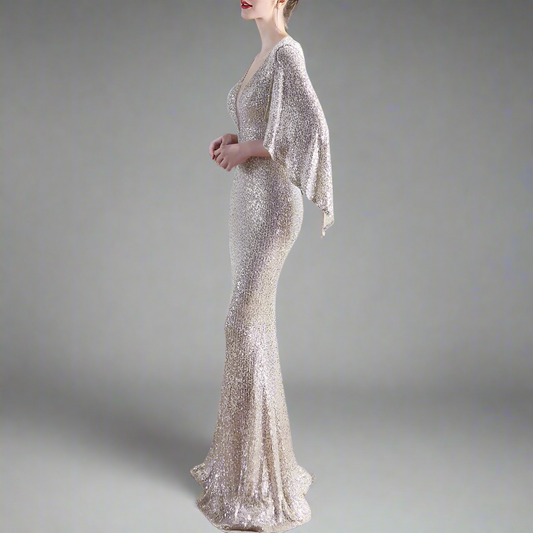 Woman wearing a sparkly silver evening gown with cape bat sleeves