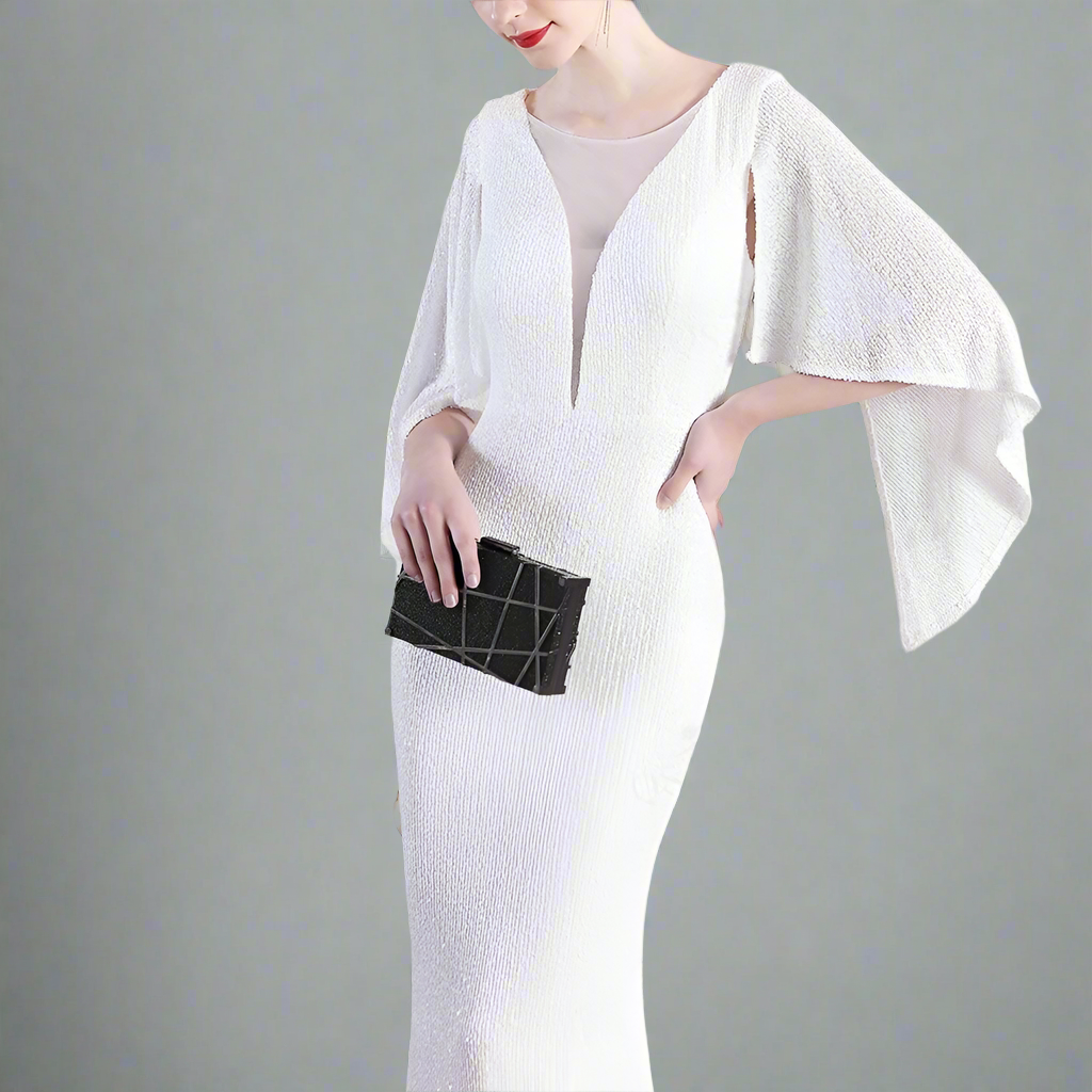 Woman in a white sparkling dress holding a black clutch.