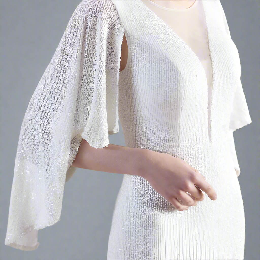 White sequined dress with cape sleeves with blurred background