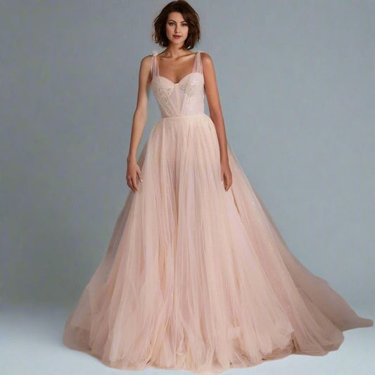 Woman in a light pink tulle evening dress with embroidery and lace and tulle straps.