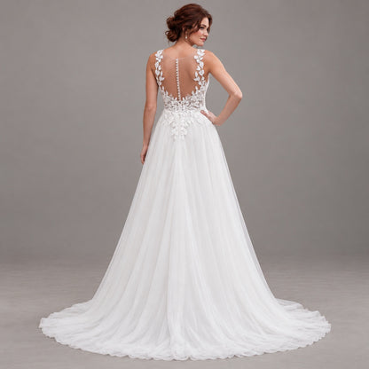 A woman modeling a white wedding gown from the back, showing a deep V-back with floral lace applique, a beaded waistband, and a full tulle train against a neutral gray studio background.
