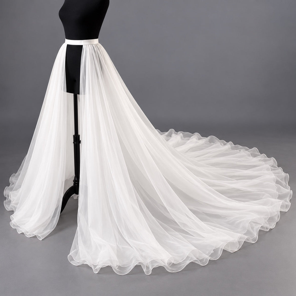 A long, flowing white organza skirt displayed on a black mannequin against a plain gray studio background.