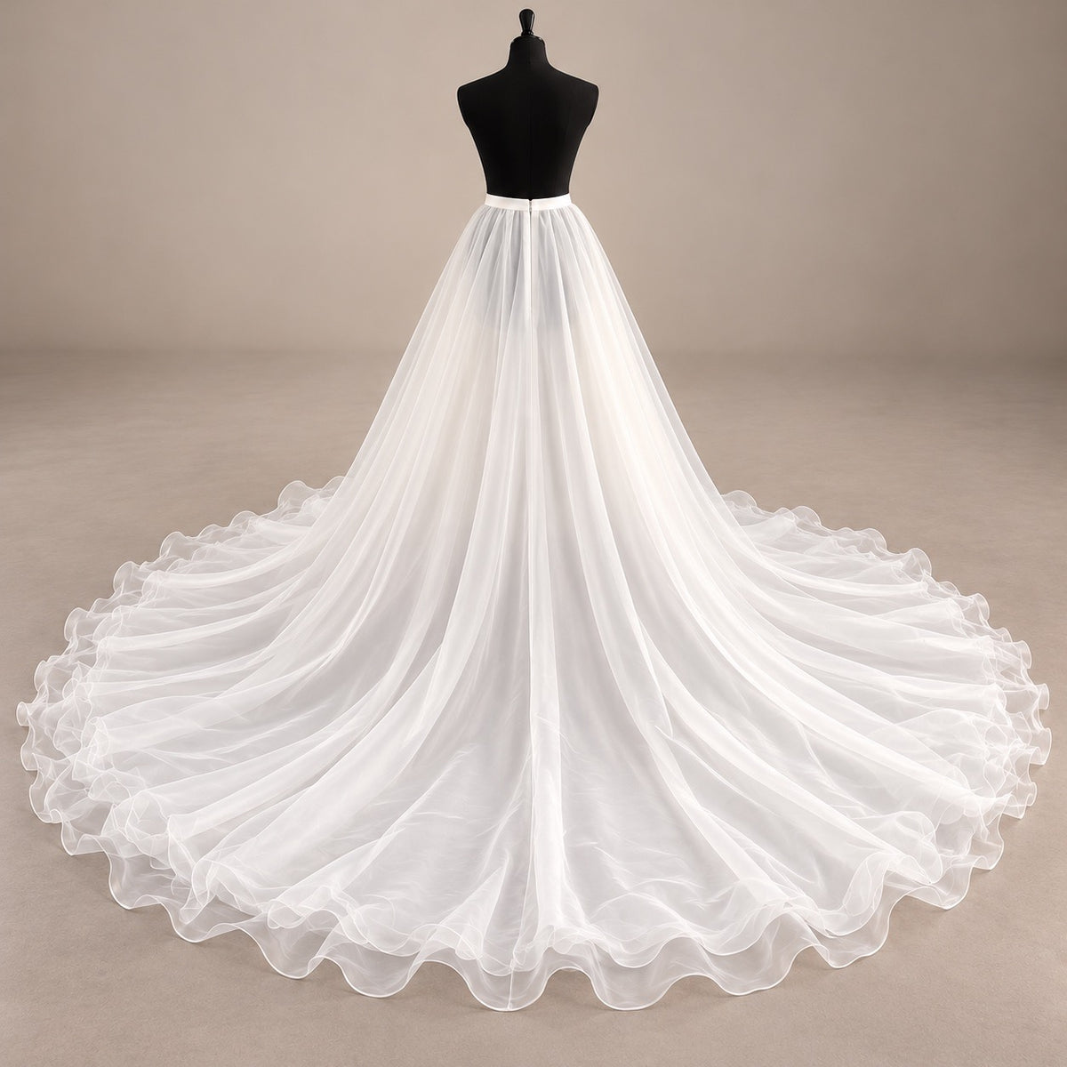 A white organza wedding dress displayed on a black mannequin torso against a plain beige studio background. The dress has a fitted bodice and a very full, flowing skirt with a long train spread wide across the floor.
